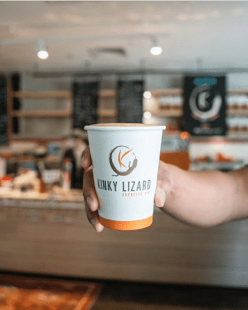 A hand reaching holding the KInky Lizard Coffee