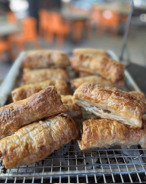 A picture of sausage rolls under a tray.