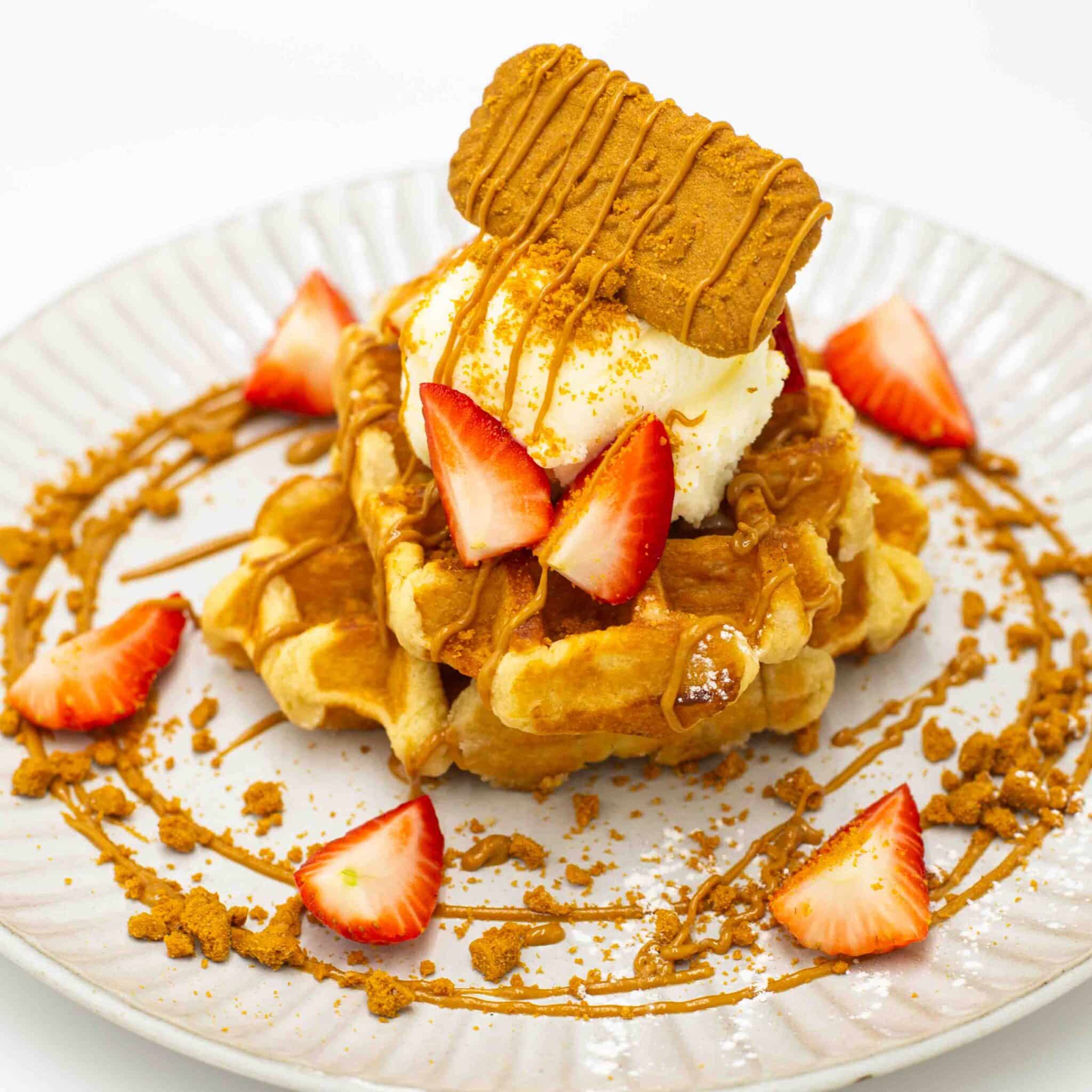 Dessert with vanilla ice cream, crumb topping, caramel drizzle, and sliced strawberries on a white plate.